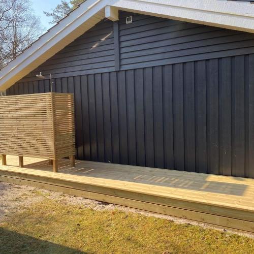 Ny terrasse med en udendørs bruser ved et sommerhus