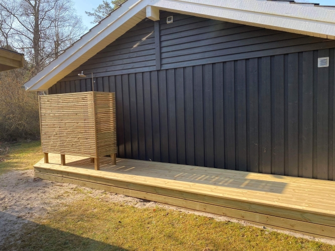 Ny terrasse med en udendørs bruser ved et sommerhus
